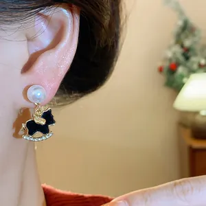 Close-up of elegant gold rocking horse pearl drop earrings featuring sparkling rhinestones