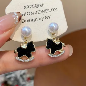 Exquisite detail view of black enamel rocking horse earrings with pearls and crystals.