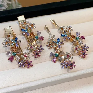 Elegant gold metal hair clips with sparkling rhinestone flower designs in jewelry tray