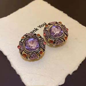 Elegant vintage geometric stud earrings with purple crystals and an antique gold finish
