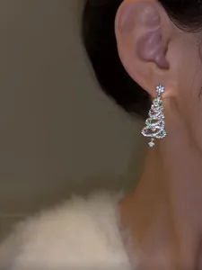 Close-up of sparkling Christmas tree earrings with colorful zircons worn on ear.