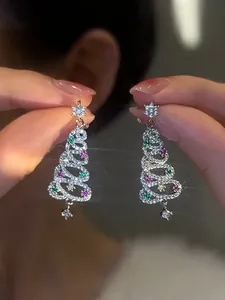 Detail view of sparkling Christmas tree earrings with colorful zircons and snowflake stud.