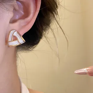 Close-up of a French retro triangle stud earring with white enamel and gold trim