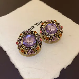 Close-up detail of vintage ornate earrings with purple center stone and rhinestones