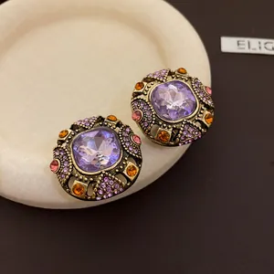 Detail view of vintage palace style earrings with purple gemstones and colorful rhinestones