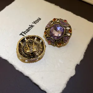 Close-up of vintage purple crystal earrings with antique gold metal and rhinestone details