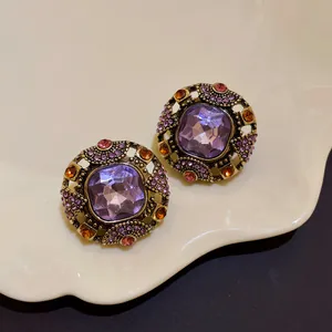 Macro view of vintage palace-style stud earrings with purple crystals and rhinestones