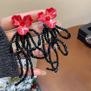 Detailed macro view of elegant red flower stud earrings with long black beaded tassels