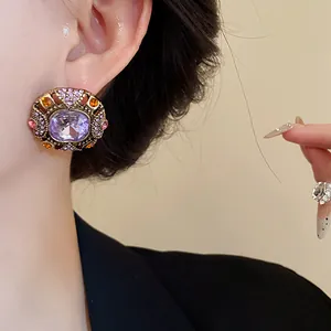 Close-up detail of vintage palace style stud earrings featuring a large purple crystal