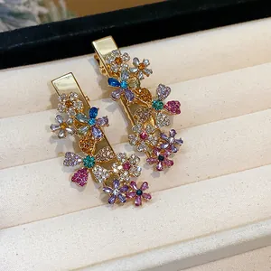 Detailed macro view of elegant gold hair clips with colorful rhinestone flower patterns.