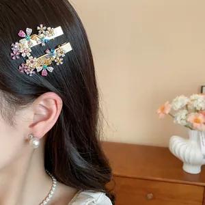 Close-up of sparkling colorful rhinestone flower hair clips styled on dark hair with pearl earrings