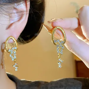 Nahaufnahme eleganter Gold-Quastenohrringe mit Strasssteinen und filigranen Designdetails.