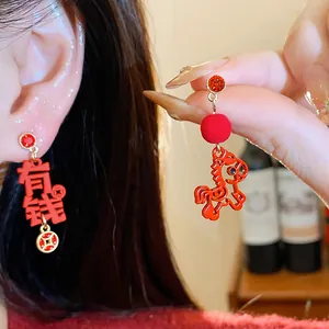 Macro view of festive red earrings featuring zodiac horse and auspicious symbols
