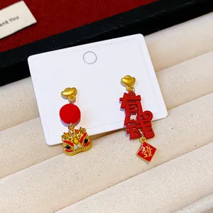 Close-up of asymmetric red New Year earrings with lion head and Chinese characters