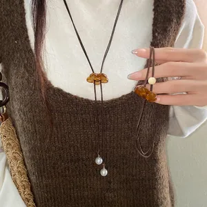 Elegant brown resin flower pendant necklace with white pearl charms worn by a model
