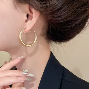 Primo piano di un orecchino a clip a forma di C in oro minimalista sull'orecchio del modello
