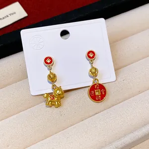 Detailed view of red and gold Chinese New Year earrings with horse and coin charms.