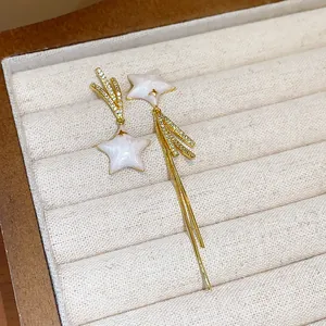 Detailed close-up of luxury asymmetric gold-plated star earrings with zircon in jewelry box
