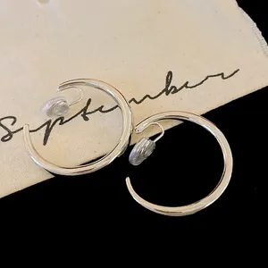 Primo piano di orecchini a clip a forma di C in argento minimalista per orecchie senza buco