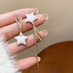 Close-up detail of asymmetric star earrings with 18k gold plating and sparkling zircons