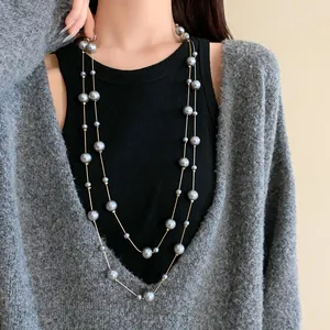 Detailed shot of long double-layer necklace with elegant grey faux pearls on model.