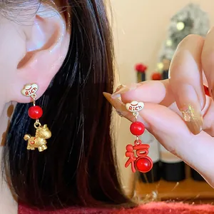 Detailed close-up of festive red and gold asymmetric earrings with horse and Fu character