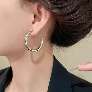 Primo piano dettagliato di orecchini a clip a cerchio argentati minimalisti a forma di C.