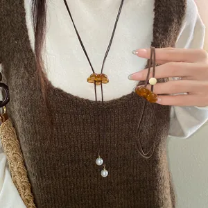 Detailed view of an amber resin flower pendant necklace with pearls worn on model
