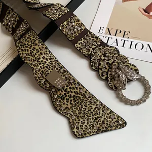 Dettaglio cintura larga leopardata con fibbia a farfalla impreziosita da strass.