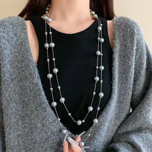 Detailed view of grey multi-layered artificial pearl long necklace on female model.