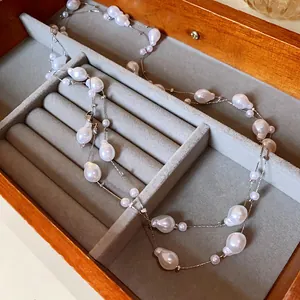 Detailed view of an elegant long faux pearl necklace inside a velvet jewelry box.