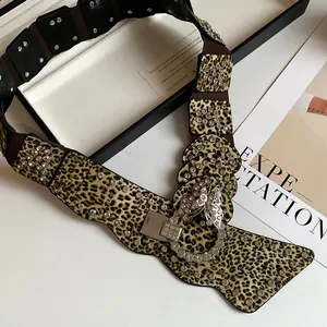 Dettaglio di una cintura larga leopardata con fibbia a farfalla in strass scintillanti.