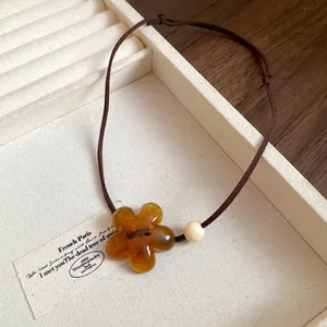 Detailed macro view of an amber resin flower pendant necklace on a jewelry tray.