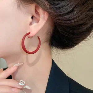 Primo piano dettagliato di un orecchino a clip a forma di C rosso opaco sull'orecchio