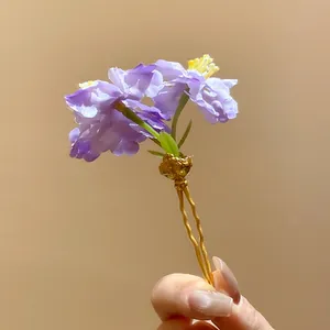 Close-up detail of an elegant purple fabric flower hairpin with a golden wavy hair fork