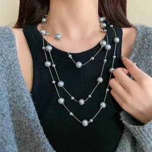 Detailed view of an elegant grey multi-layer long faux pearl necklace worn by a model