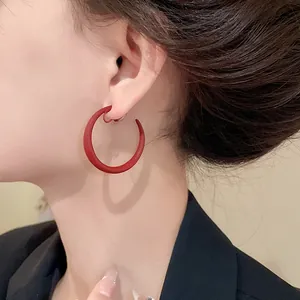 Primo piano laterale di orecchini a clip rossi opachi a forma di C su una modella
