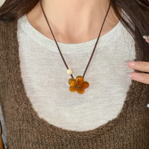 Close-up view of amber resin flower pendant necklace on a minimalist brown cord
