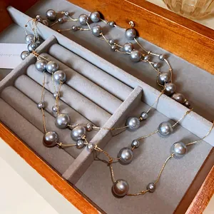 Detailed close-up of an elegant French style long necklace with grey faux pearls