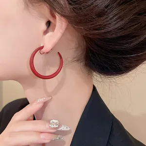 Primo piano di orecchini a clip a forma di C rossi opachi indossati da una modella