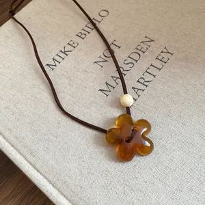 Detailed close-up of a stylish amber resin flower pendant necklace on a book background