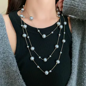 Close-up of elegant grey pearl layered long necklace on a model wearing a cardigan