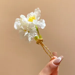Detailed macro shot of a white fabric flower hair pin with a golden metal fork