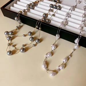 Detail view of elegant gray and white pearl long necklaces displayed on jewelry tray.