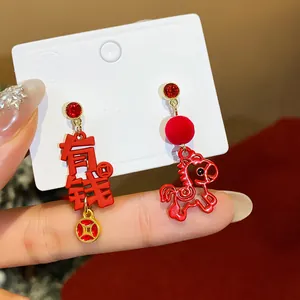 Detail shot of red New Year earrings featuring a decorative horse and Chinese coin charms