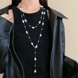 Detailed view of long layered faux pearl necklace worn over a black leather jacket