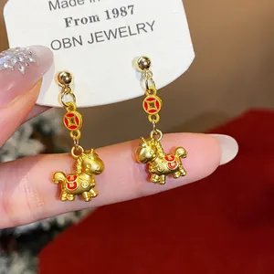 Detailed view of golden horse stud earrings with red enamel lucky coin accents