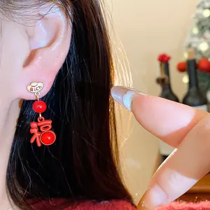 Detailed close-up of model wearing festive red Fu character and Rich cloud earrings.
