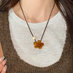 Close-up detail of an amber resin flower pendant necklace worn by an Asian model