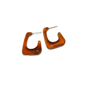 Retro amber-colored resin hoop earrings with silver pins on a white background.